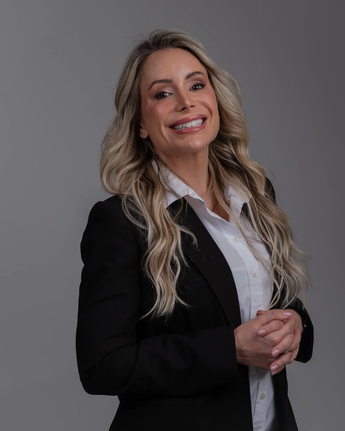 Retrato da Dra. Fernanda Simone Gehm, de blazer preto, sobre fundo cinza